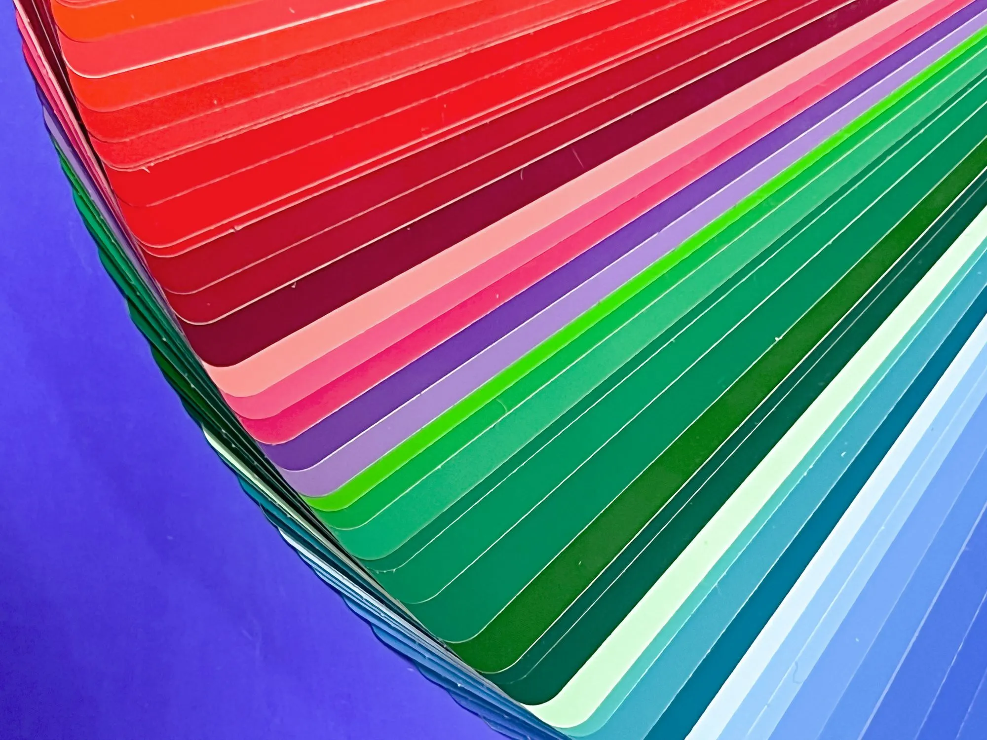 A fan deck of paint colour cards splayed open across reds, greens and blues