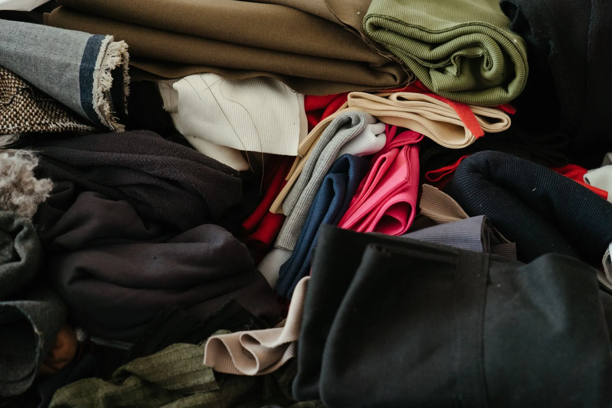 A stack of folded fabrics in olive, red, navy and cream