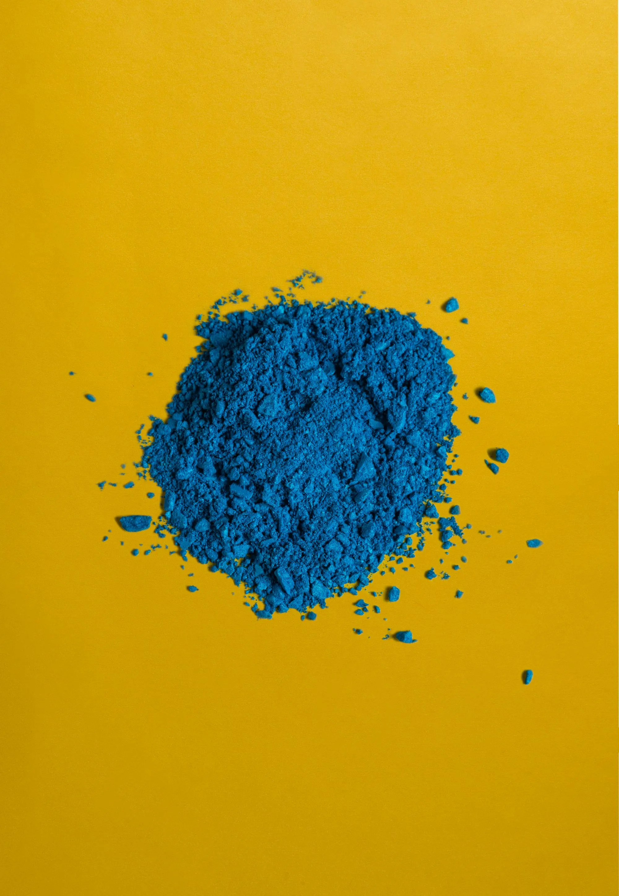 A heap of blue pigment powder, coarsely broken, on a yellow ground