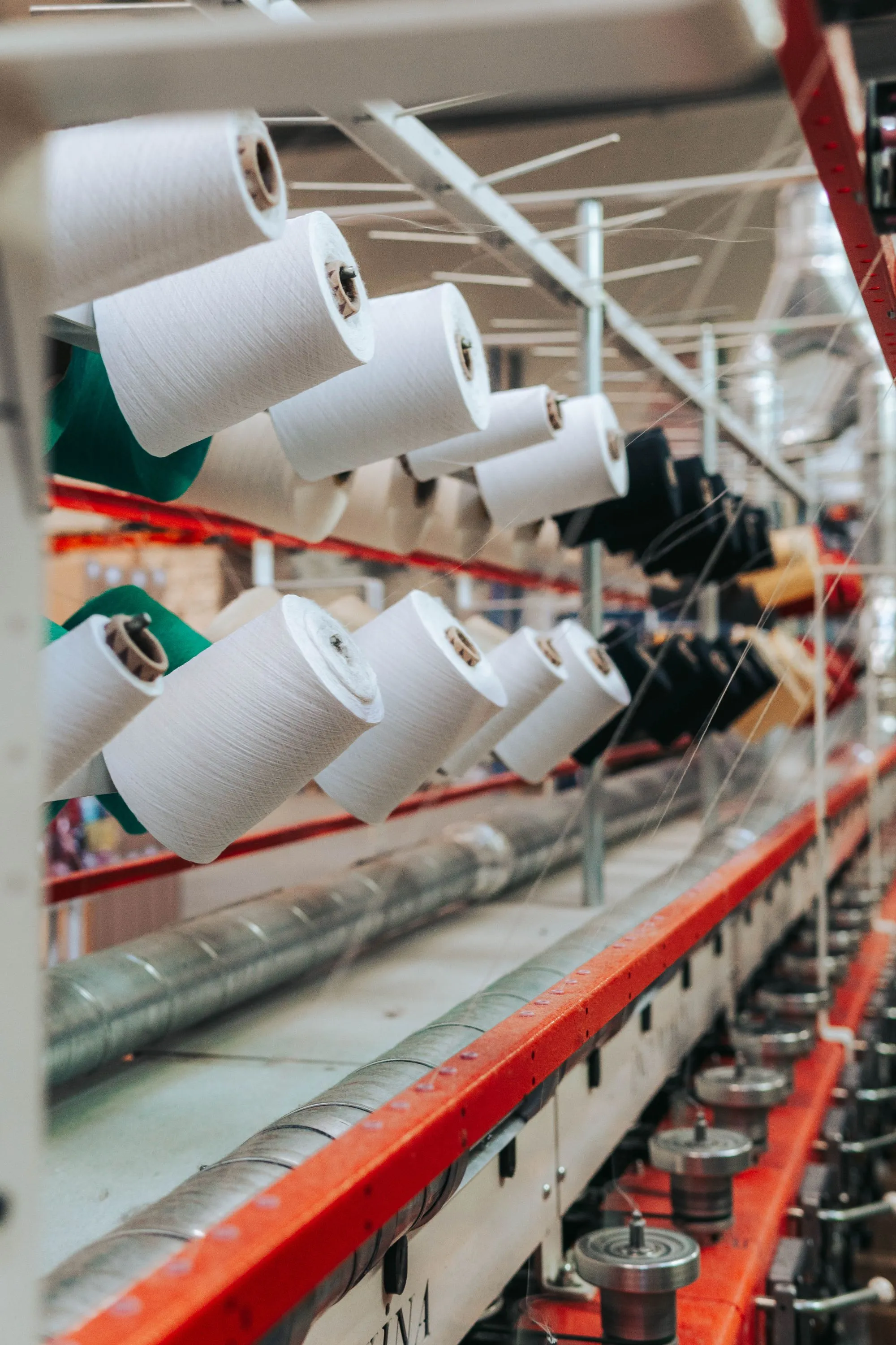 Rows of white yarn cones on a spinning frame in a textile mill